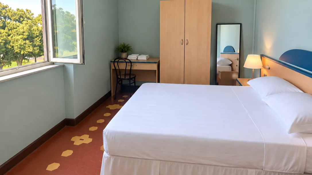 Bedroom with double bed, wooden wardrobe, full-length mirror, desk and red floor with yellow geometric details - Hotel Rex, BZAR hotels in Lucca