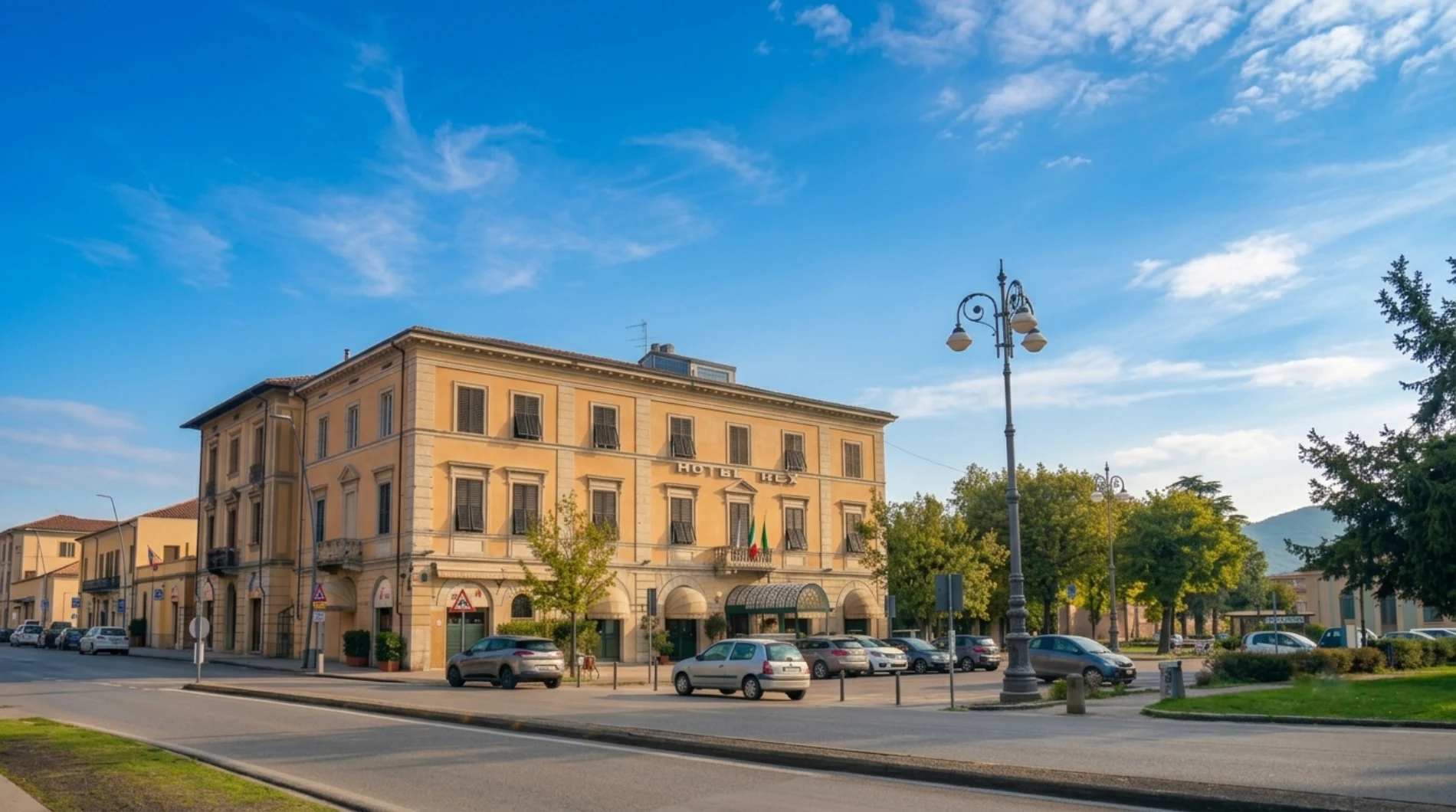 Hotel exterior facade with historic building, street entrance, nearby parking and blue sky - Hotel Rex, BZAR hotels in Lucca