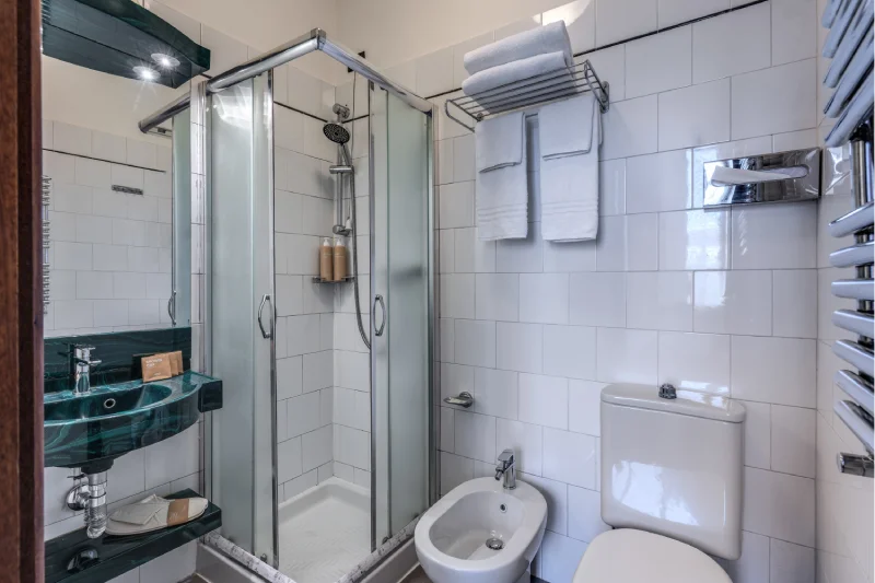Bathroom with black sink, large mirror, glass shower, hairdryer and beige courtesy set - Hotel Rex, BZAR hotels in Lucca