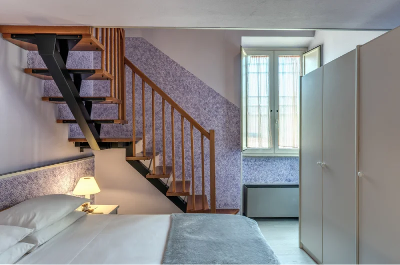 Family room with internal staircase, double bed, light wardrobe, bright window and TV on cabinet - Hotel Rex, BZAR hotels in Lucca