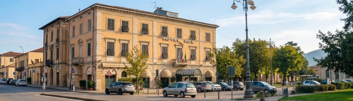 Historic hotel exterior facade with sign, street entrance, nearby parking and blue sky - Hotel Rex, BZAR hotels in Lucca