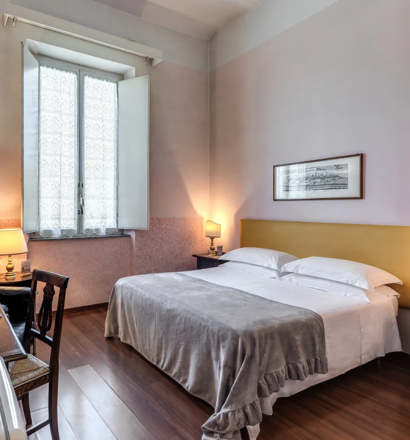 Bright double room with large bed, mustard headboard, wooden floor and tall window - Hotel Rex, BZAR hotels in Lucca