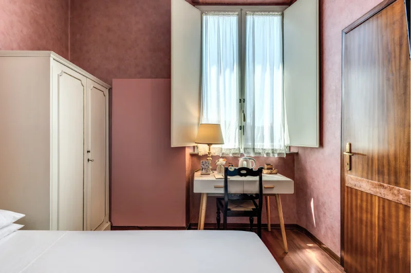 Single room with light wardrobe, desk below the window, kettle and elegant pink walls - Hotel Rex, BZAR hotels in Lucca