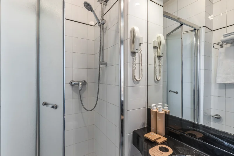 Room bathroom with shower enclosure, black sink, mirror, towels, hairdryer and courtesy set - Hotel Rex, BZAR hotels in Lucca