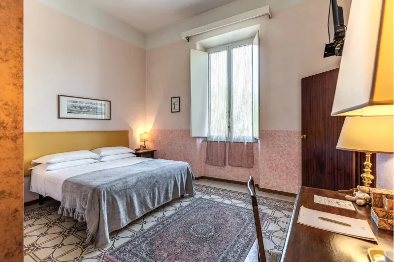 Bright suite with double bed, tall window, classic rug, desk and warm lamps - Hotel Rex, BZAR hotels in Lucca