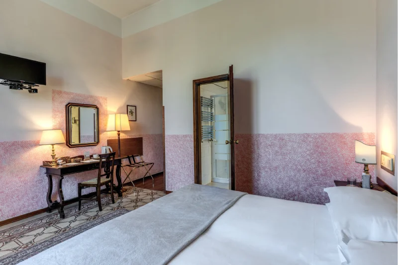 Suite with double bed, desk, classic mirror, wall-mounted TV and visible private bathroom - Hotel Rex, BZAR hotels in Lucca