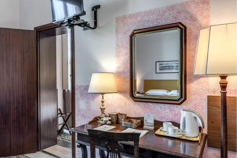 Suite detail with vintage desk, classic mirror, wall-mounted TV, kettle and courtesy set - Hotel Rex, BZAR hotels in Lucca