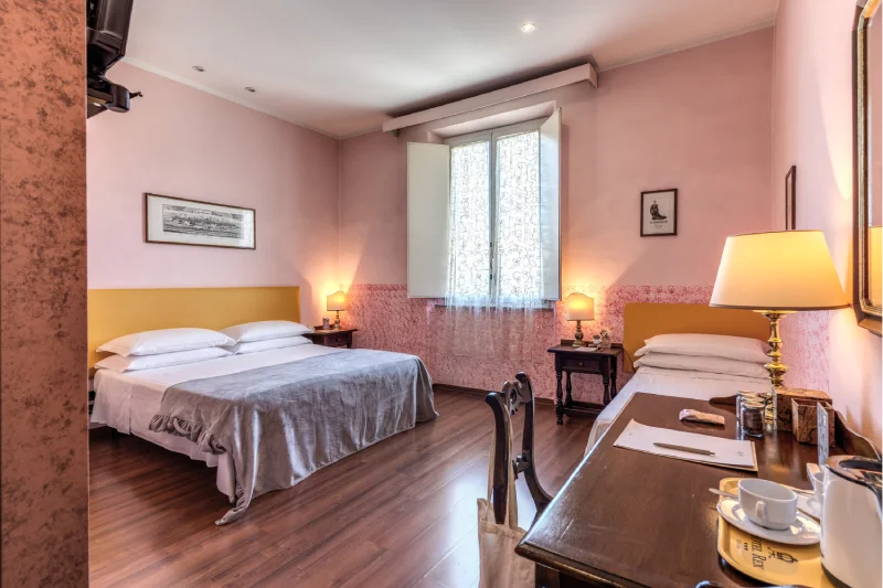 Spacious triple room with double bed, single bed, desk, bright window and pink walls - Hotel Rex, BZAR hotels in Lucca