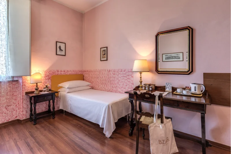 Triple room with single bed, wooden desk, mirror, kettle, lamp and window with curtains - Hotel Rex, BZAR hotels in Lucca